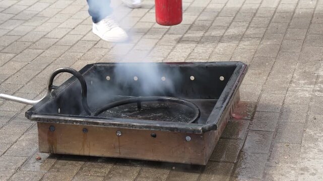 White smoke rising from a metal training pan after extinguishing flames during a professional fire safety and emergency response drill