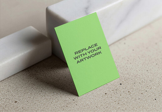 Business card mockup leaning against a white marble block on speckled stone surface, realistic stationery presentation with placeholder text, vertical design