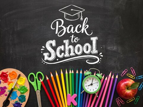 Back to school message written in chalk on a blackboard with colorful pencils scissors paint palette and a red apple for education design