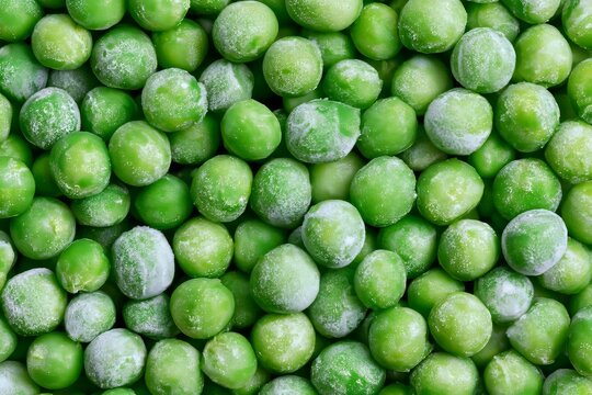 Frozen green peas scattered on a surface ready for cooking or adding to dishes