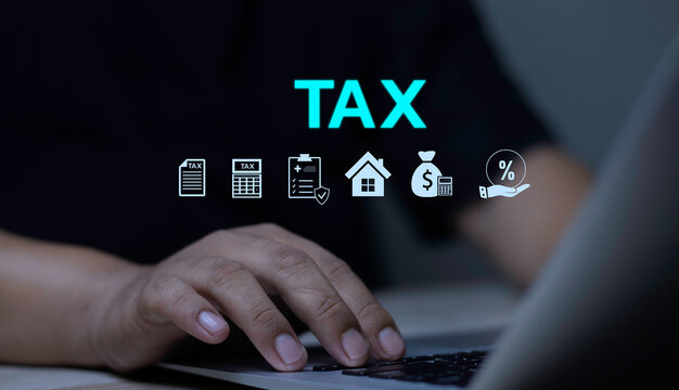 E-filing tax system, online tax return, and financial accounting concept with close up hand typing on laptop keyboard with TAX icon line and financial symbols.