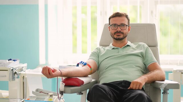 Male blood donor giving blood at donation center