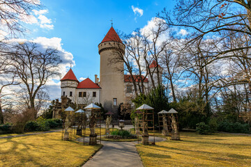 Medieval castle with red roof turrets in serene forest setting © Iurii Gagarin