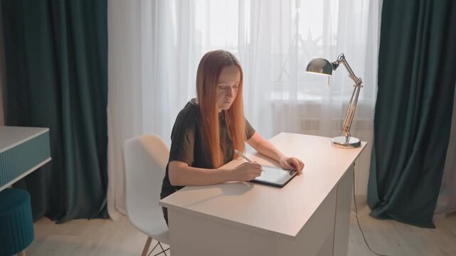 Woman engaged actively through her hands and eyes towards. Teal accents on small stool next to table or shelf unit. Bedroom setting includes beige sofa bed patterned rugs