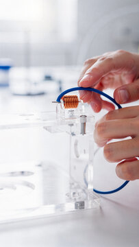 Engineer Assembling Copper Coil Inductor on Acrylic Rig in Laboratory