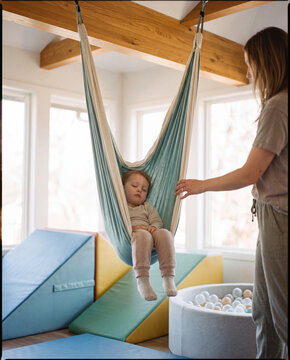 Child resting in a fabric sensory swing during pediatric therapy