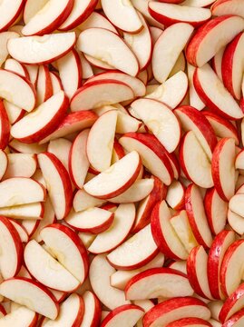 Sliced red apple wedges arranged in a dense food pattern and crisp texture in a vertical potrait orientation for recipe books, marketing assets, and culinary website backgrounds.