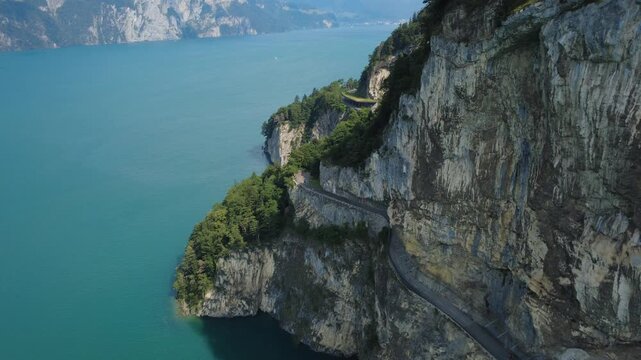 Luftaufnahme eines t&uuml;rkisen Bergsees mit steiler Felswand und eingeschnittener Stra&szlig;e, Walensee-Region