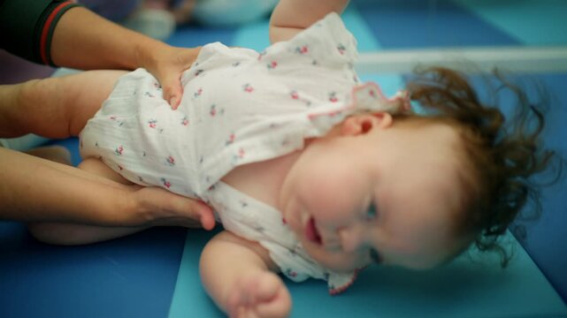 Infant lying on a mat, undergoing physical therapy exercises to promote healthy growth and motor skill development