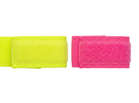 Elastic wrist strap sports band set in bright neon yellow and pink isolated on black background for fitness, exercise, training equipment, adjustable hook and loop fastener, studio closeup photography