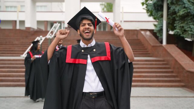 Joyful indian graduate celebrating with diploma on campus