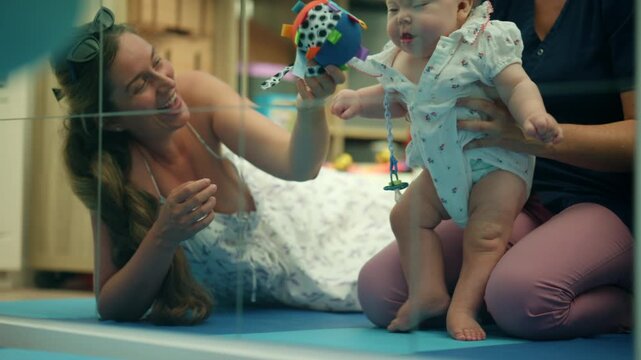 Mother and therapist working with a baby during early intervention physical therapy, helping with motor skill development