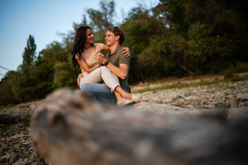 Fototapeta premium Young couple enjoying outdoor date sitting on log