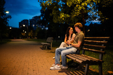 Fototapeta premium Young couple enjoying romantic night conversation in city park