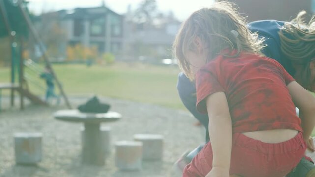 Close-up of two boys playing together on playground equipment in backlight