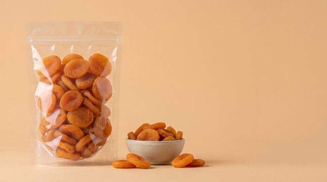 Dried apricots packaged in clear bag on beige surface