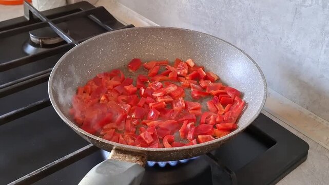 Chopping and cooking red peppers in a pan on the stove