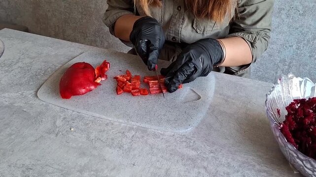 Person cuts red bell pepper and prepares food at home kitchen