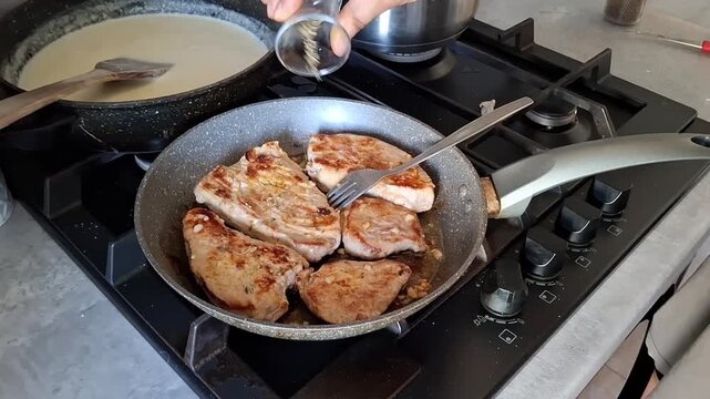 Cooking pork in the kitchen while adding spices to enhance flavor during afternoon preparation