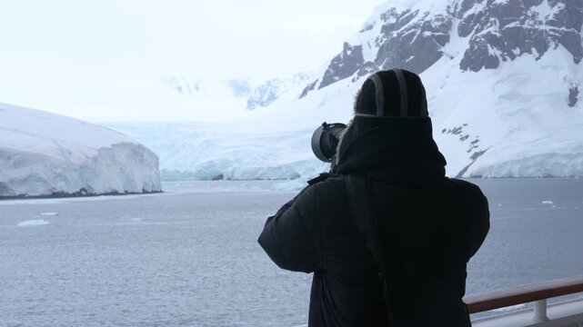 Antarctica Cruise Ship Male Photographer Takes Photos with Professional Telephoto Lens. Over the Shoulder Black Hat, Gloves, Coat Glacier Landscape