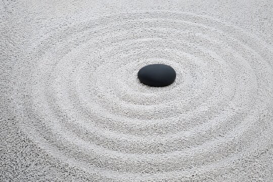 Zen raked white gravel wave pattern with single smooth black river pebble