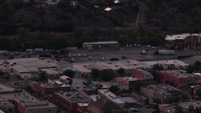 Aerial of commercial district and mountains in Durango Colorado in evening with industrial sites and parking lots and buildings
