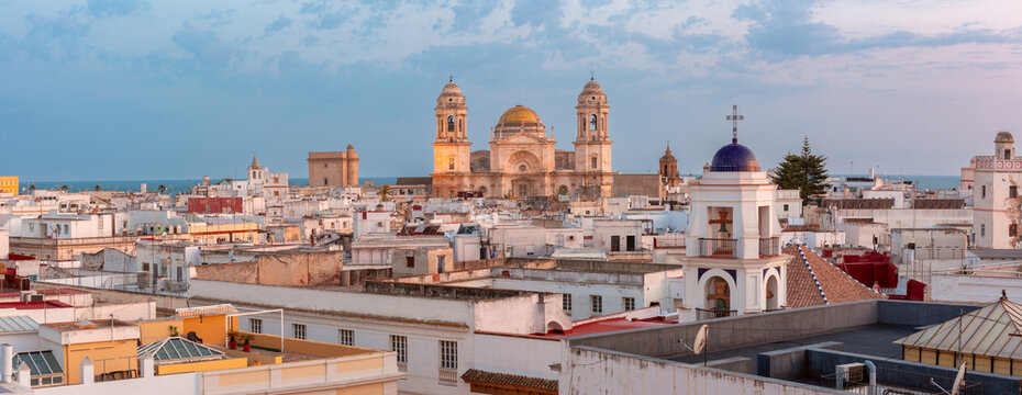 Cadiz Cathedral rises above whitewashed rooftops and church towers with the Atlantic Ocean visible beyond the city, Spain.