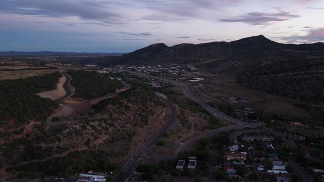 Wide aerial of town nestled in mountain valley in Durango Colorado at dusk with major highway US 160 running through the valley floor in summer