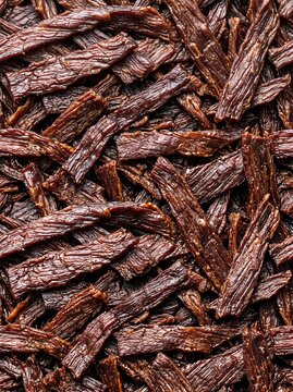 Slices of beef jerky create a detailed food texture and organic pattern in this vertical potrait layout for snack packaging and culinary marketing materials.