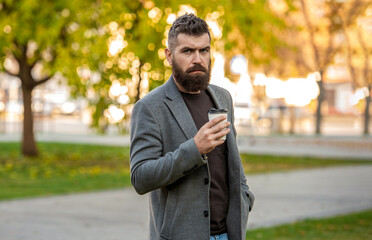 Fototapeta premium Business lifestyle, break. Man drinking morning coffee. Coffee break. Bearded man having coffee in city street. Handsome man on street holding cup coffee