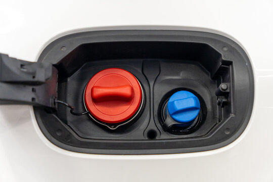 Close-up of open white car fuel filler flap with red diesel tank cap and blue AdBlue DEF fluid cap. Detailed horizontal view of modern passenger vehicle refueling neck. Concept of automobile. 
