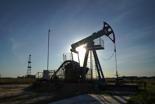 Oil extraction. Pumpjack in oil well of oil field on sunset. Industrial crude area. Crude pump jack working on petroleum extraction on sunrise. Pumpjack, drill rig, drilling derrick in oilfield. 