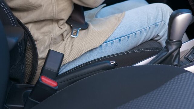 A woman unfastens her seat belt and gets out of the car. A female driver unfastens her seat belt and smoothly gets out of the car