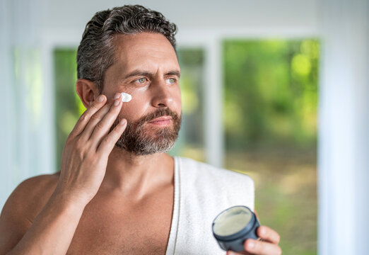 Anti-aging and wrinkle cream. Beauty man applying cosmetic cream on face. Organic cosmetics. Male beauty and skincare. Skin care. Cosmetic cream for man. Cream treatment for male face, copy space