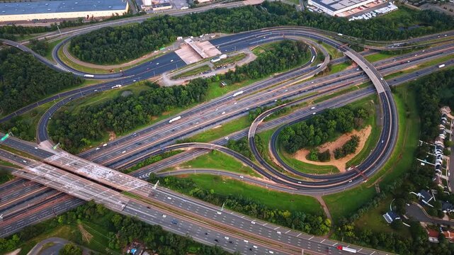 Impressive scenery of New Jersey Turnpike interchange with many cars moving by. Aerial view on the huge intersection in the area with lush greenery.