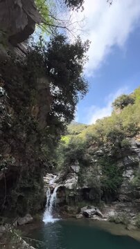 Beautiful Natural Turquoise Pool and Scenic Waterfall Flowing Between Rocky Cliffs
