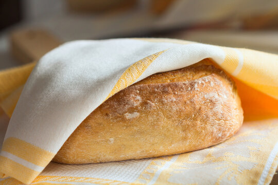 Rustic crusty homemade artisan bread loaf under linen cloth