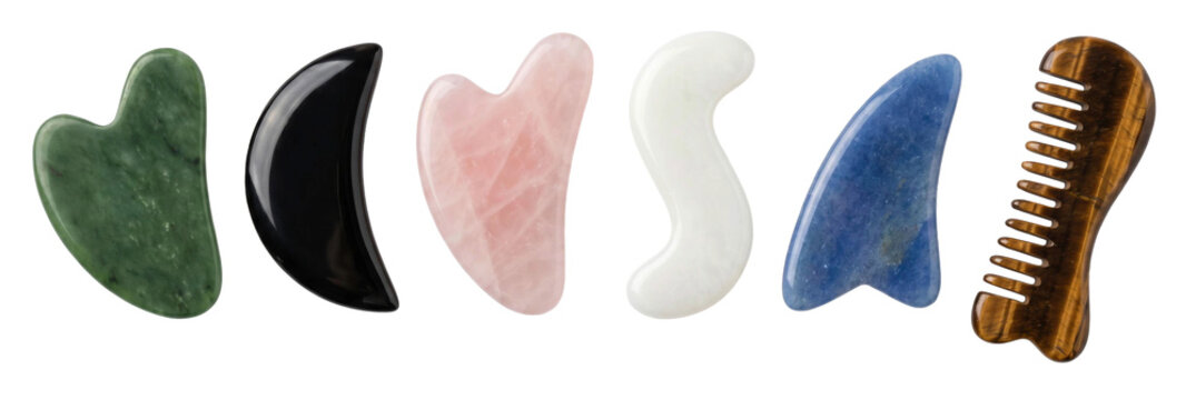 Collection of colorful gua sha tools made from natural stone for facial massage and skincare routines, featuring jade, rose quartz, obsidian, and tiger's eye scrapers and a comb