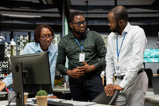 African American employees work late on goal setting while studying data insights and performance metrics and creating reports for business administration with colleagues in a strategy room.