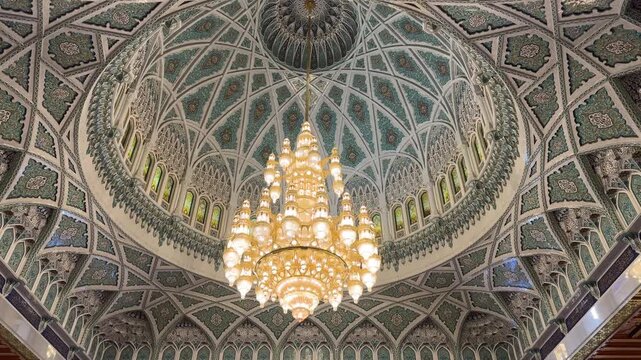 Gold plated Grand chandelier beneath ornate Islamic dome inside Sultan Qaboos Grand Mosque in Oman