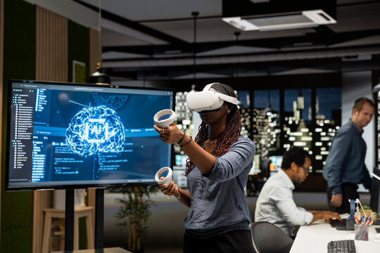 Programmer in a tech startup office uses a VR headset and artificial intelligence to automate repetitive tasks and speed up feature implementation.