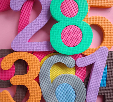 Colorful numbers background. Colorful foam puzzle numbers piled up on a pink background