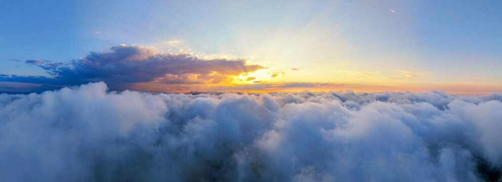 Panoramic aerial view above fluffy clouds during golden hour sunset over Black Sea in Sinop, Turkey. Stunning natural landscape with glowing sunbeams breaking through dramatic sky serene cloudscape