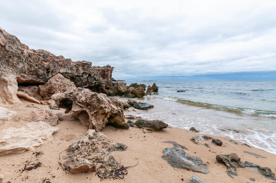 Weathered coastal rocks on a sandy beach near Perth