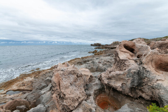 Ocean waves beside eroded cliffs and coastal vegetation