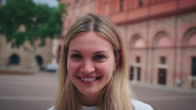 Close up Portrait of Caucasian woman looking at camera and smiling. Beautiful eastern European girl is happy and cute. She looks positive and attractive and confident laughing standing outside