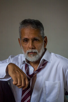 Handsome Senior Man Resting Arm on Knee Studio Portrait