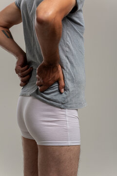 A young guy with a slender figure, dressed in white underwear, does morning exercises or massages his sore lower back before leaving for work.Body Parts: The firm male ass of a skinny middle-aged man