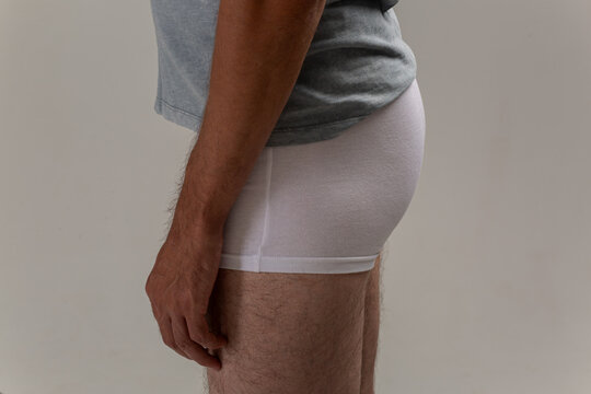 A young guy with a slender figure, dressed in white underwear, does morning exercises or massages his sore lower back before leaving for work.Body Parts: The firm male ass of a skinny middle-aged man