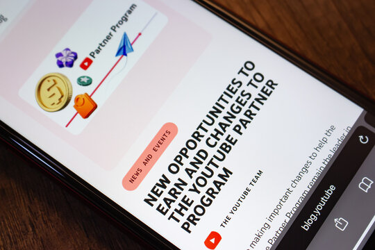 Mexico City, MEXICO - Aug 12 2026 : Close-up of an iPhone on a dark wooden table showing a post on the YouTube blog announcing new earning opportunities and changes to the Partner Program.